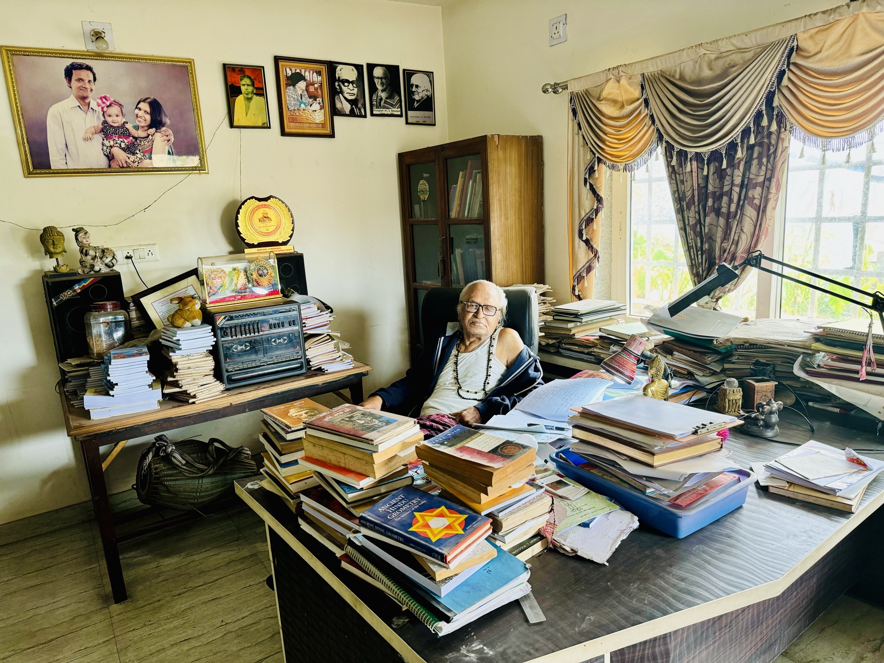 Dr. Das at his study desk, surrounded by books and papers